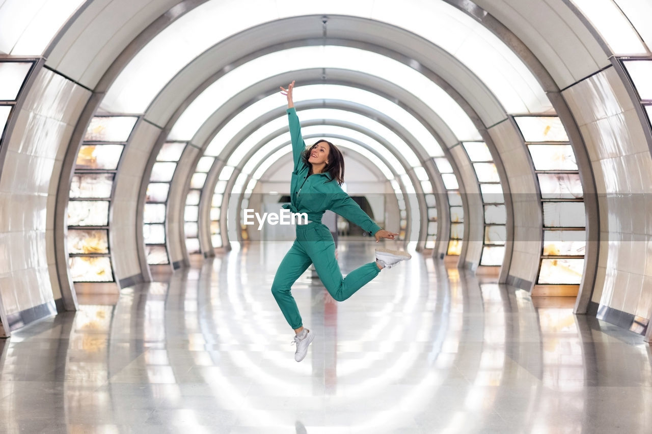 A girl in a green tracksuit jumps high up. happiness and joy, enjoyment of life. emotions jumping up