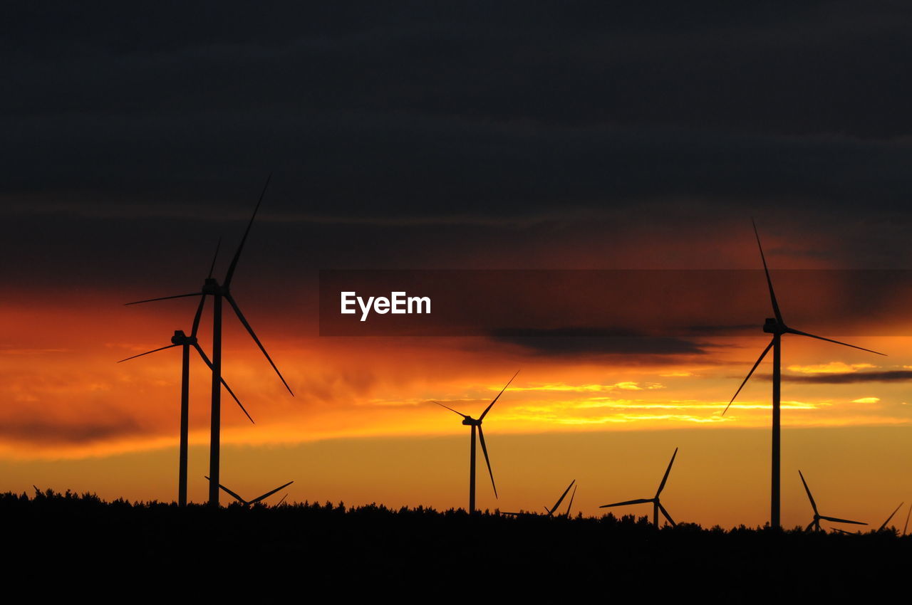 SILHOUETTE WIND TURBINES ON FIELD AGAINST SKY AT SUNSET