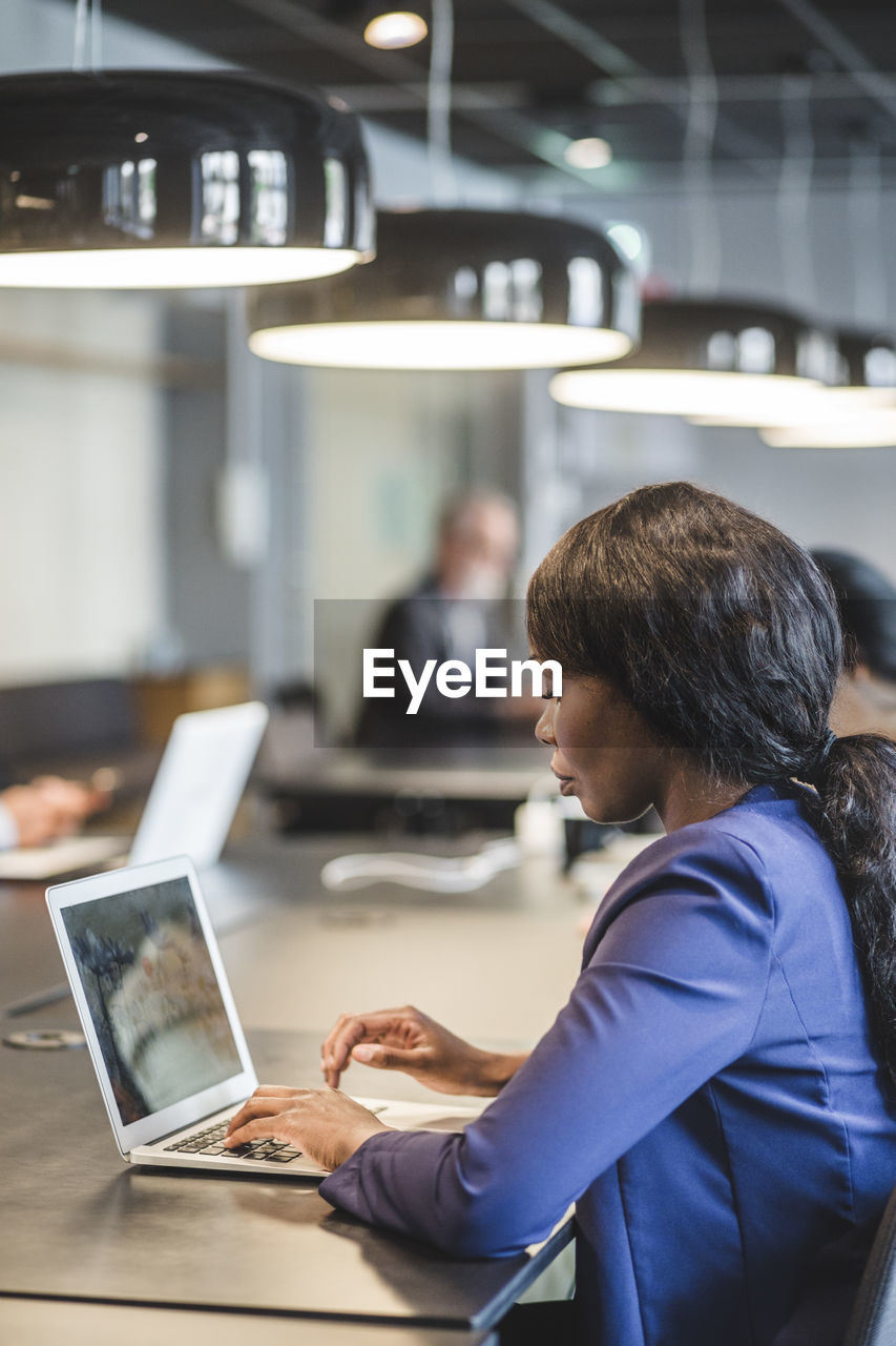 Businesswoman working over laptop while sitting at table in office