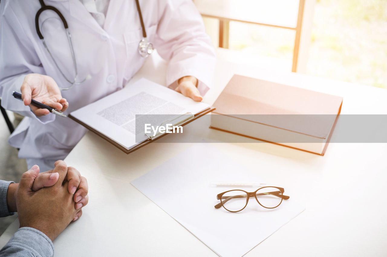 High angle view of doctor talking to patient at desk in hospital