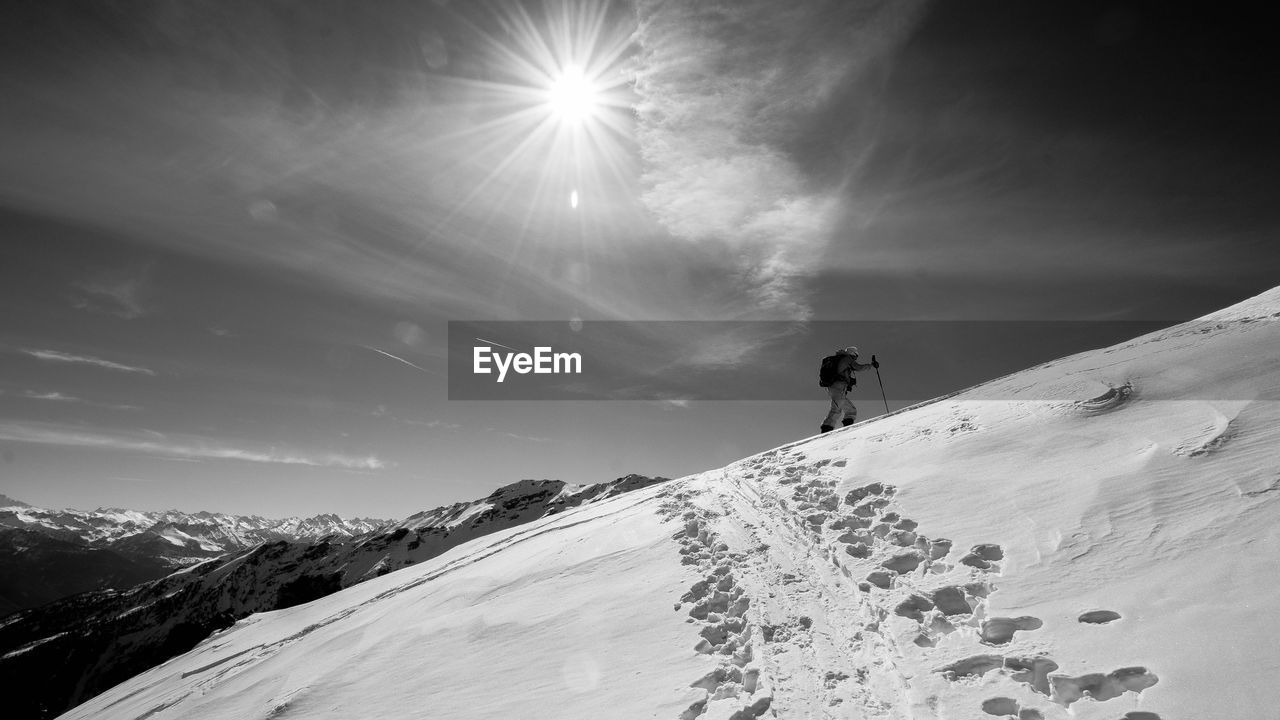 Low angle view of man hiking on snowcapped mountain against sky