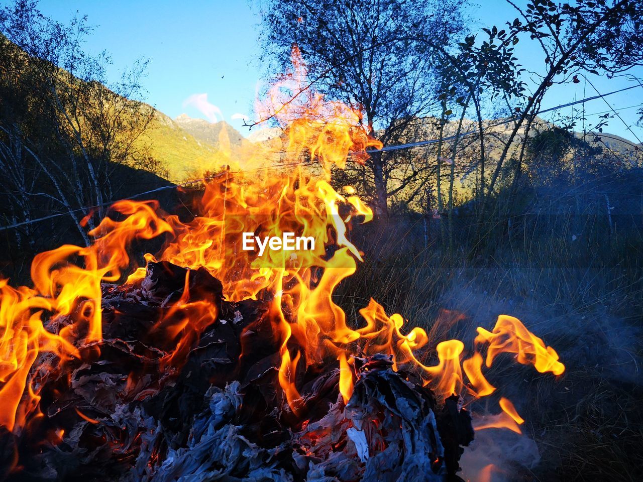 BONFIRE ON FIELD AGAINST SKY