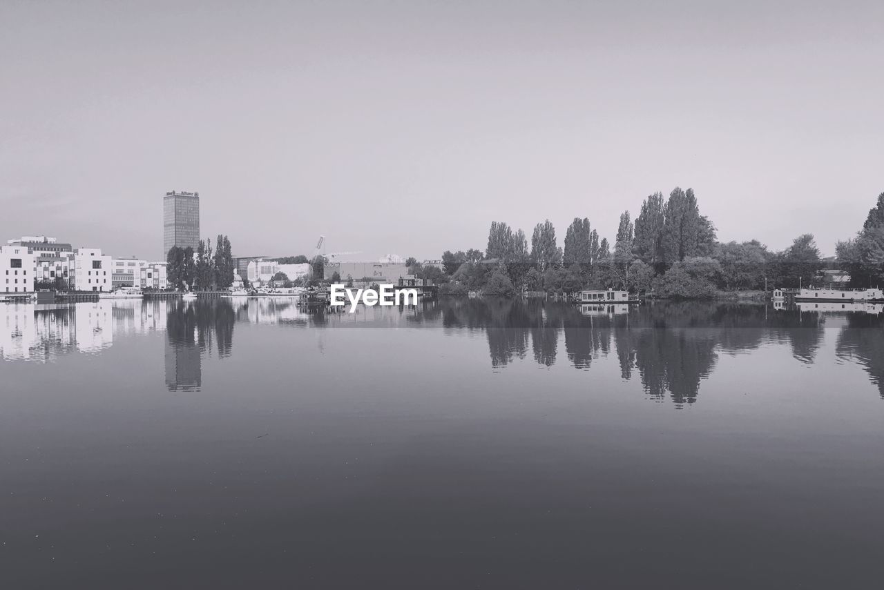 Reflection of buildings in water against clear sky