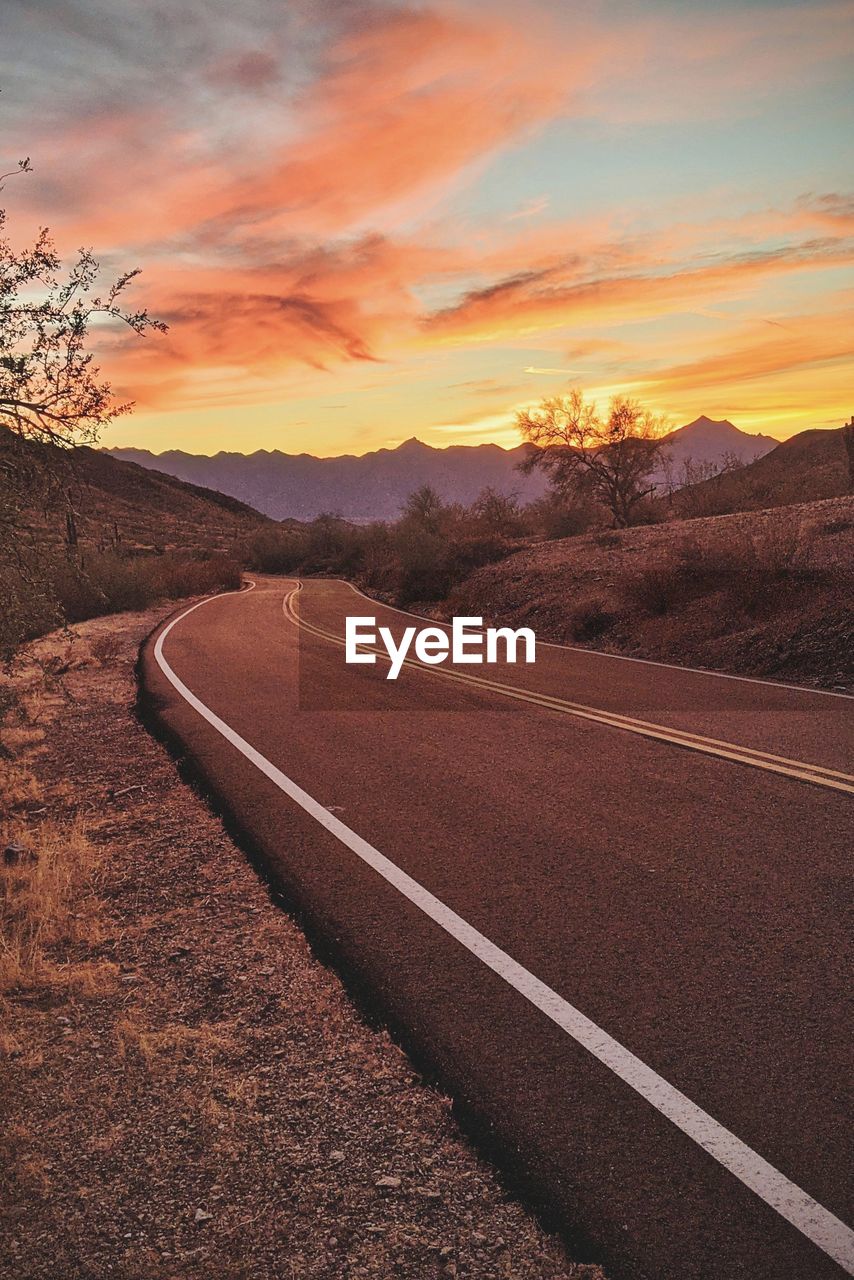 Empty road against sky during sunset