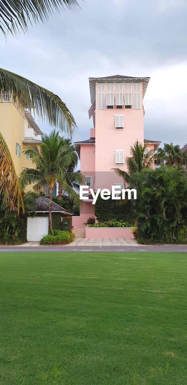 BUILDING BY PALM TREES AGAINST SKY