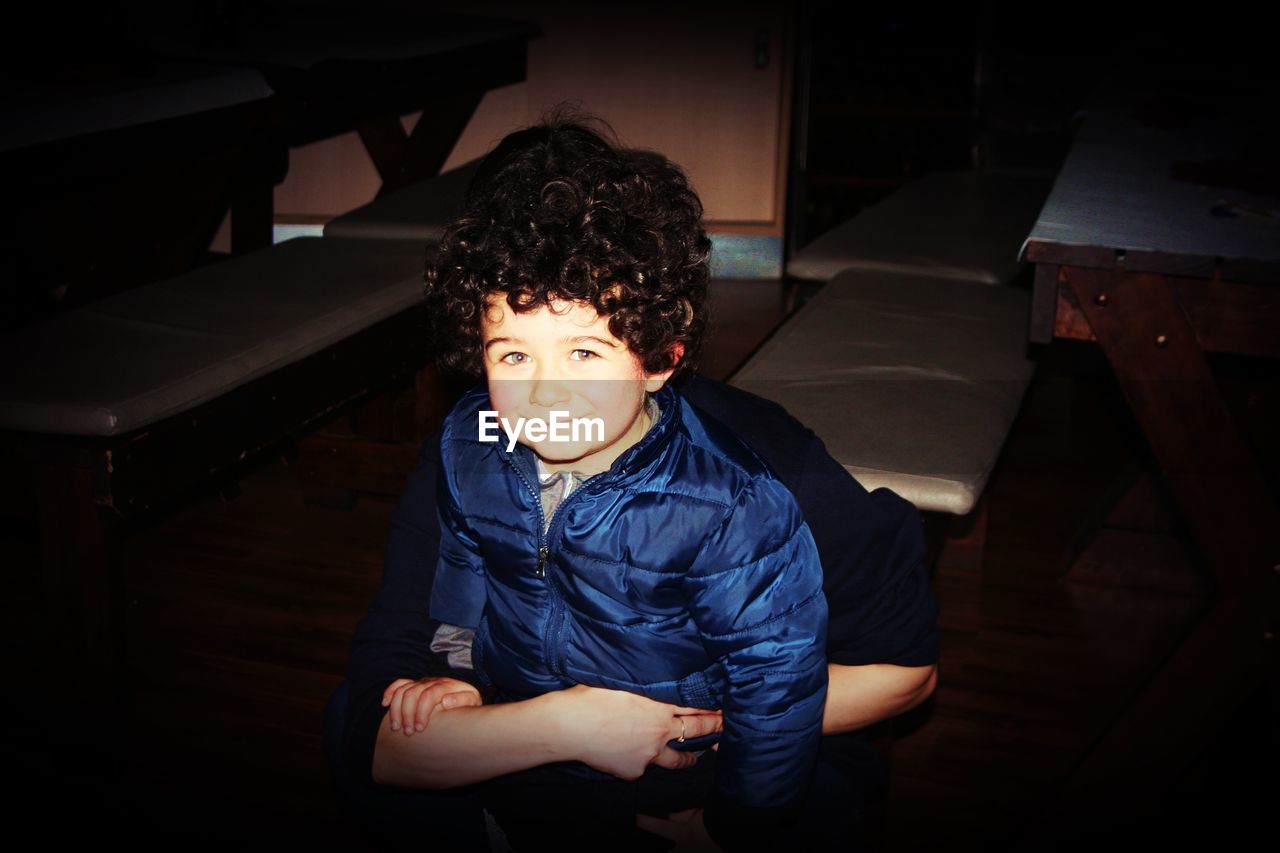 HIGH ANGLE PORTRAIT OF BOY SITTING ON SOFA AT HOME