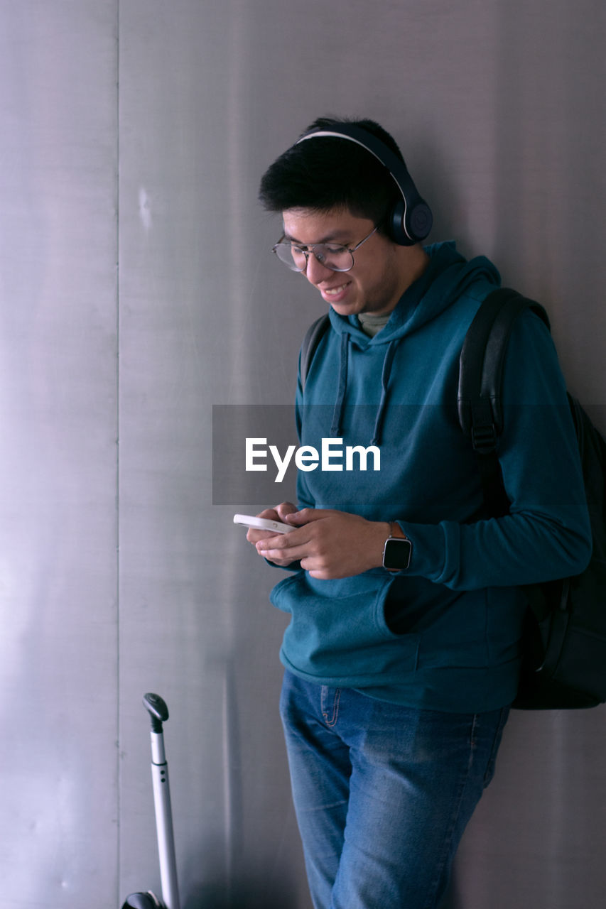 Young man smiles and is typing on his smartphone