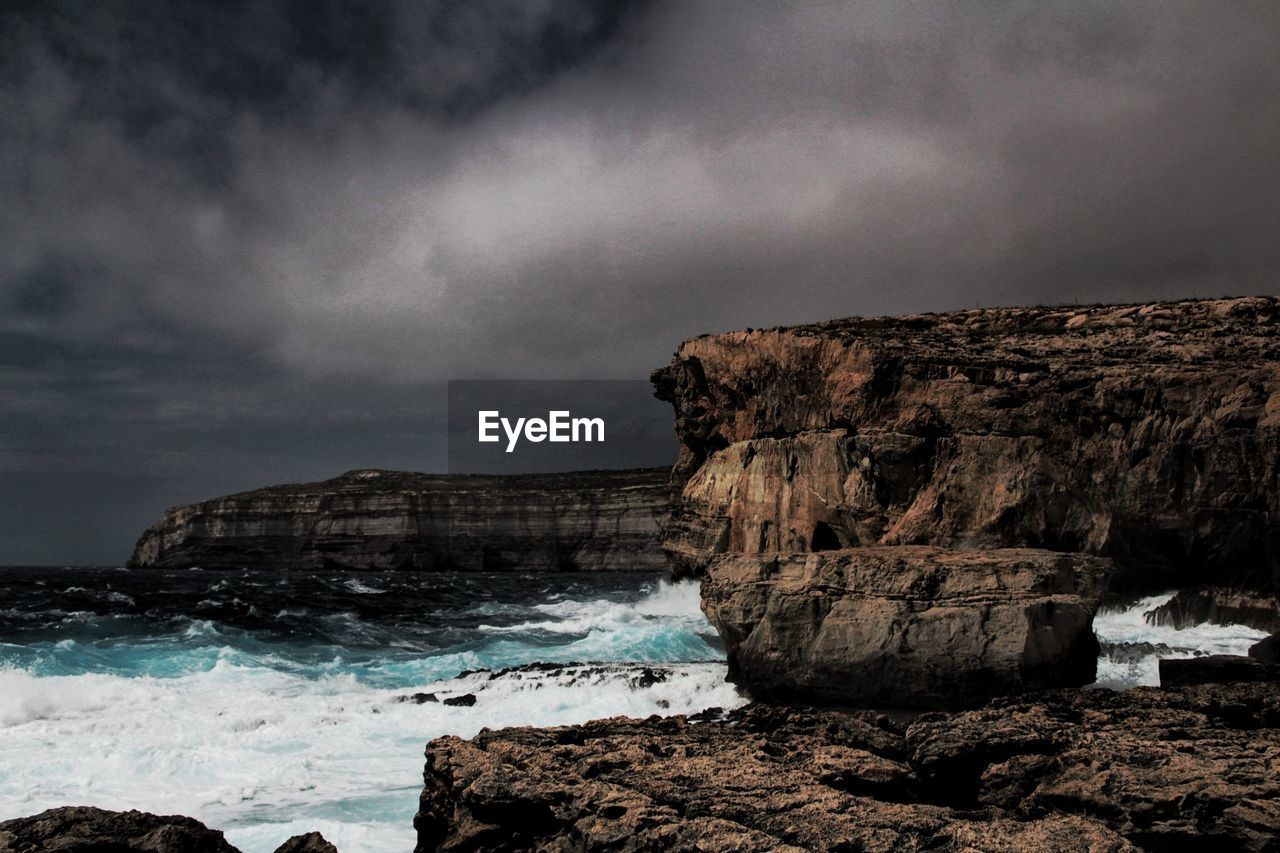 Rock formation on beach against sky