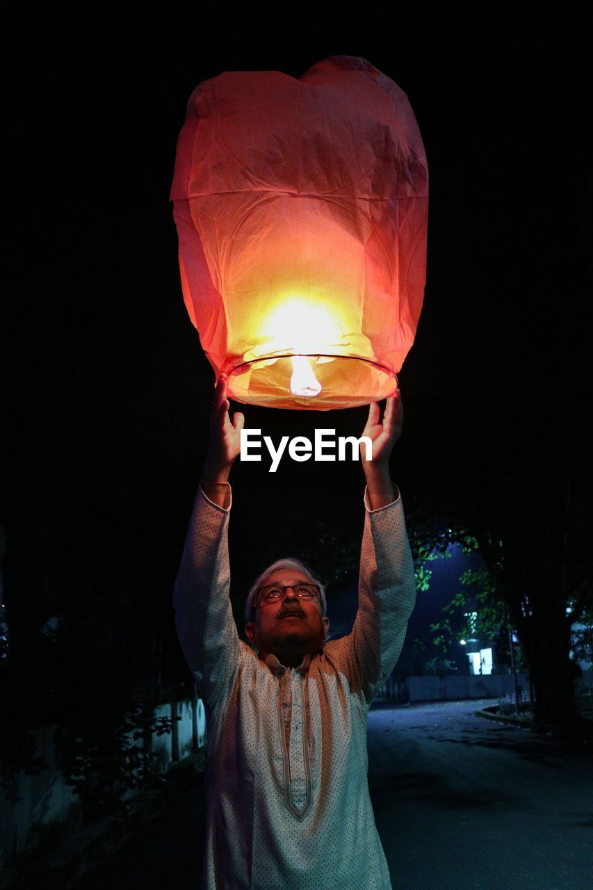 Person holding  illuminated paper lantern at night on diwali 