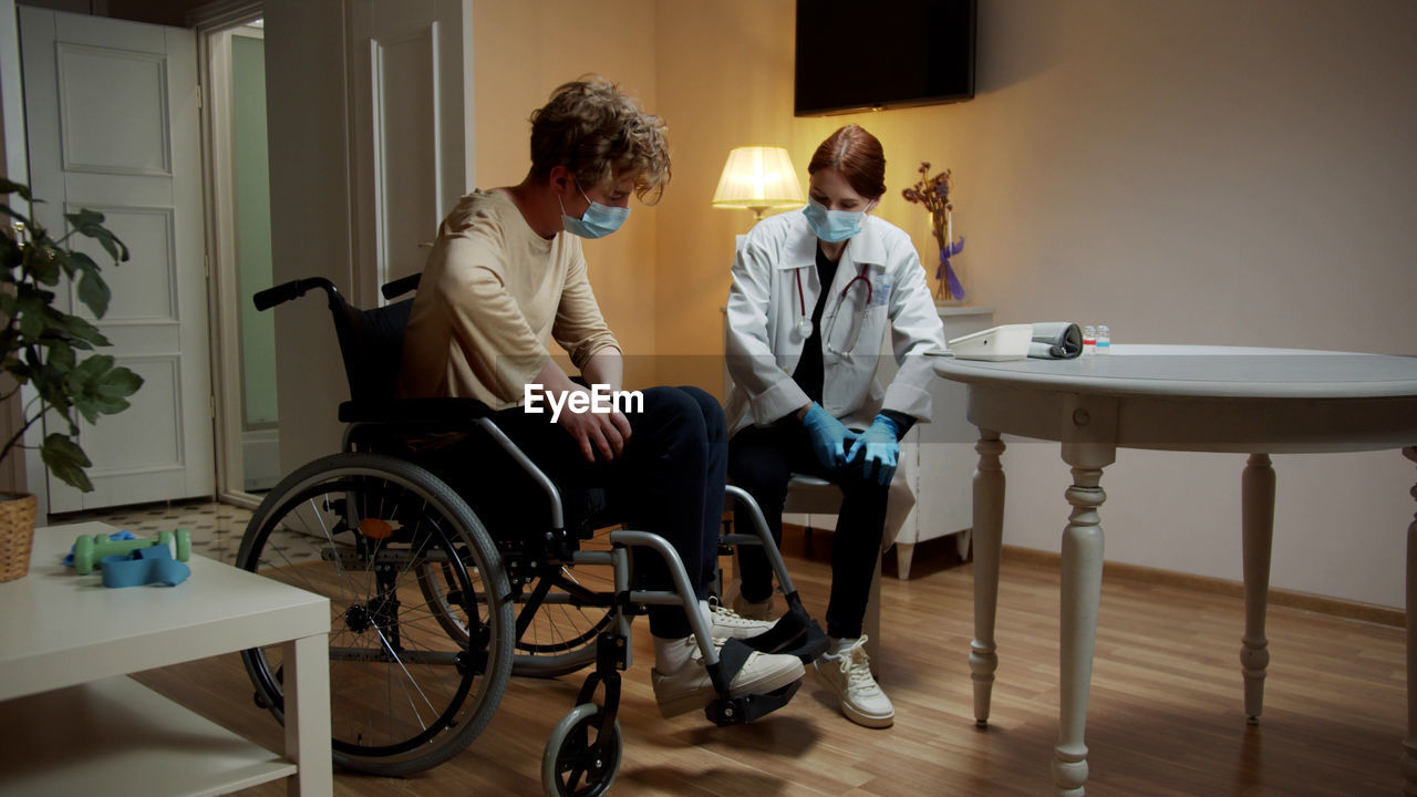 Young nurse checking temperature of patient at home