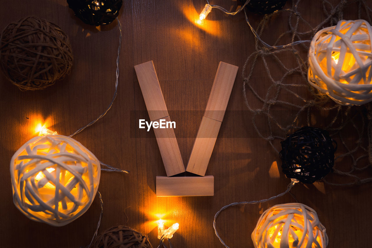 Directly above shot of letter v blocks and illuminated lights on wooden table