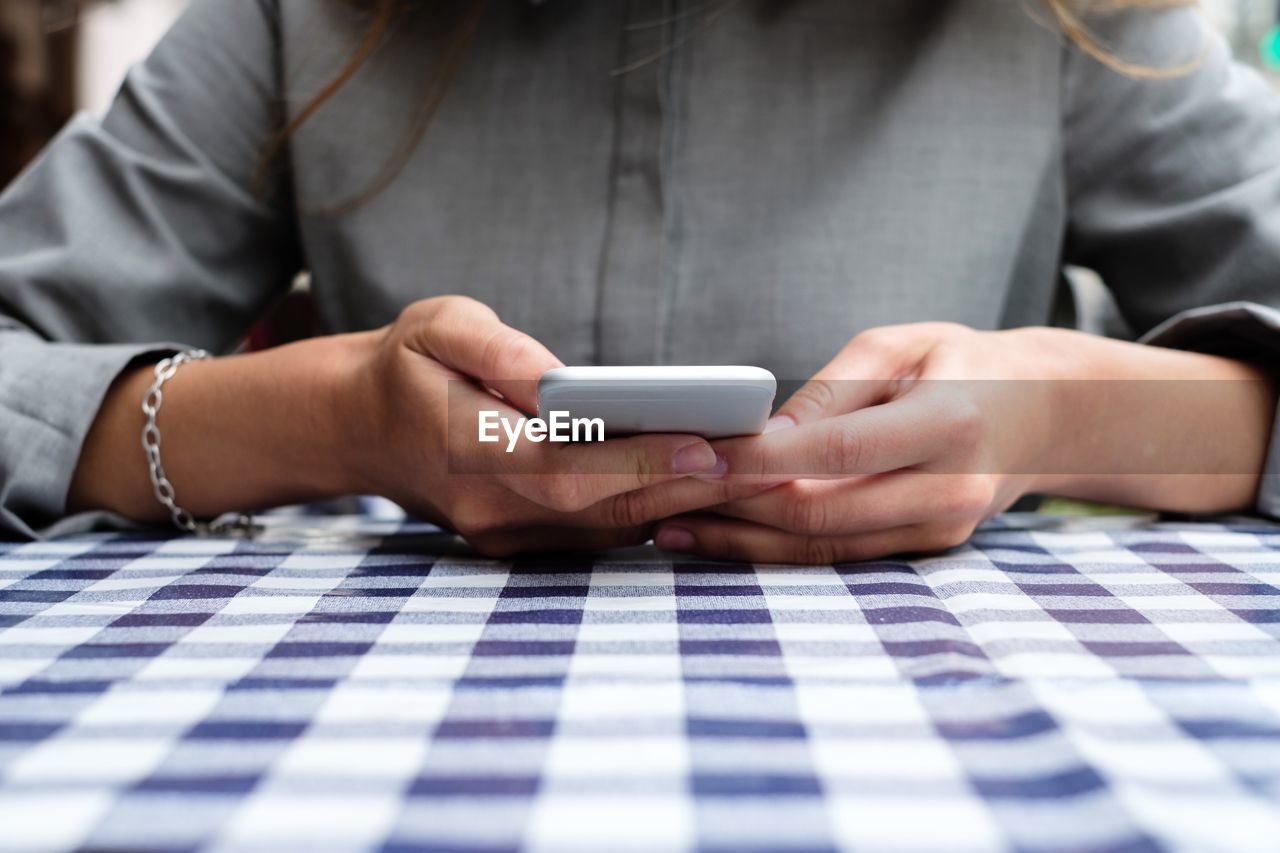 Close-up of woman using mobile phone on table