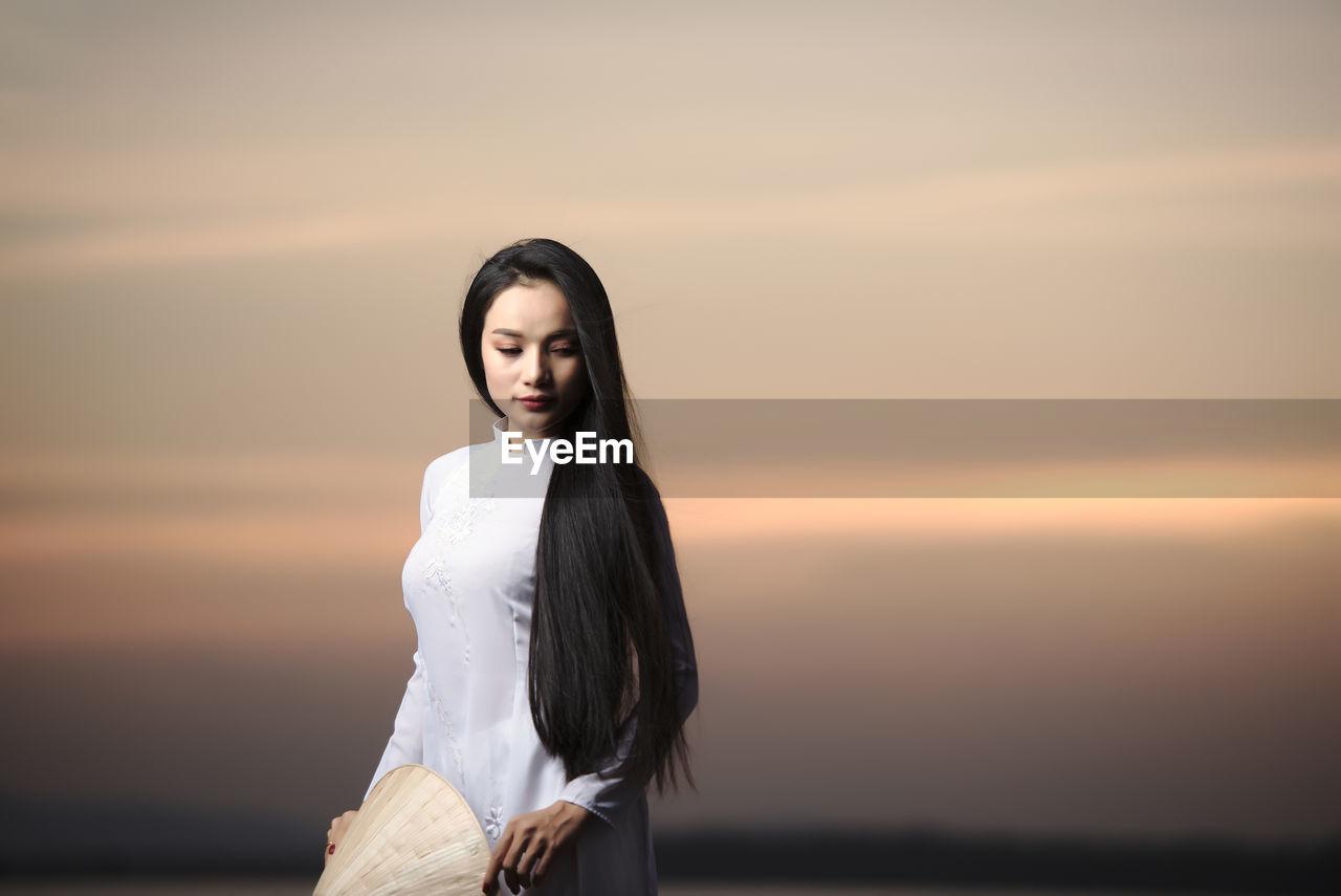 Portrait of beautiful asian girls with ao dai vietnam traditional dress on sunset landscapes.