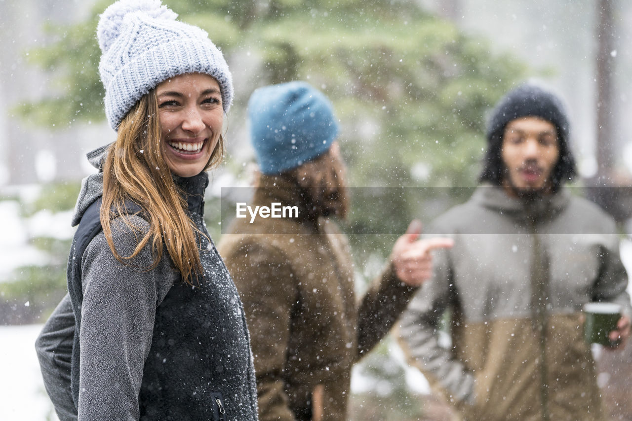 Young woman hanging out with friends in the woods in winter