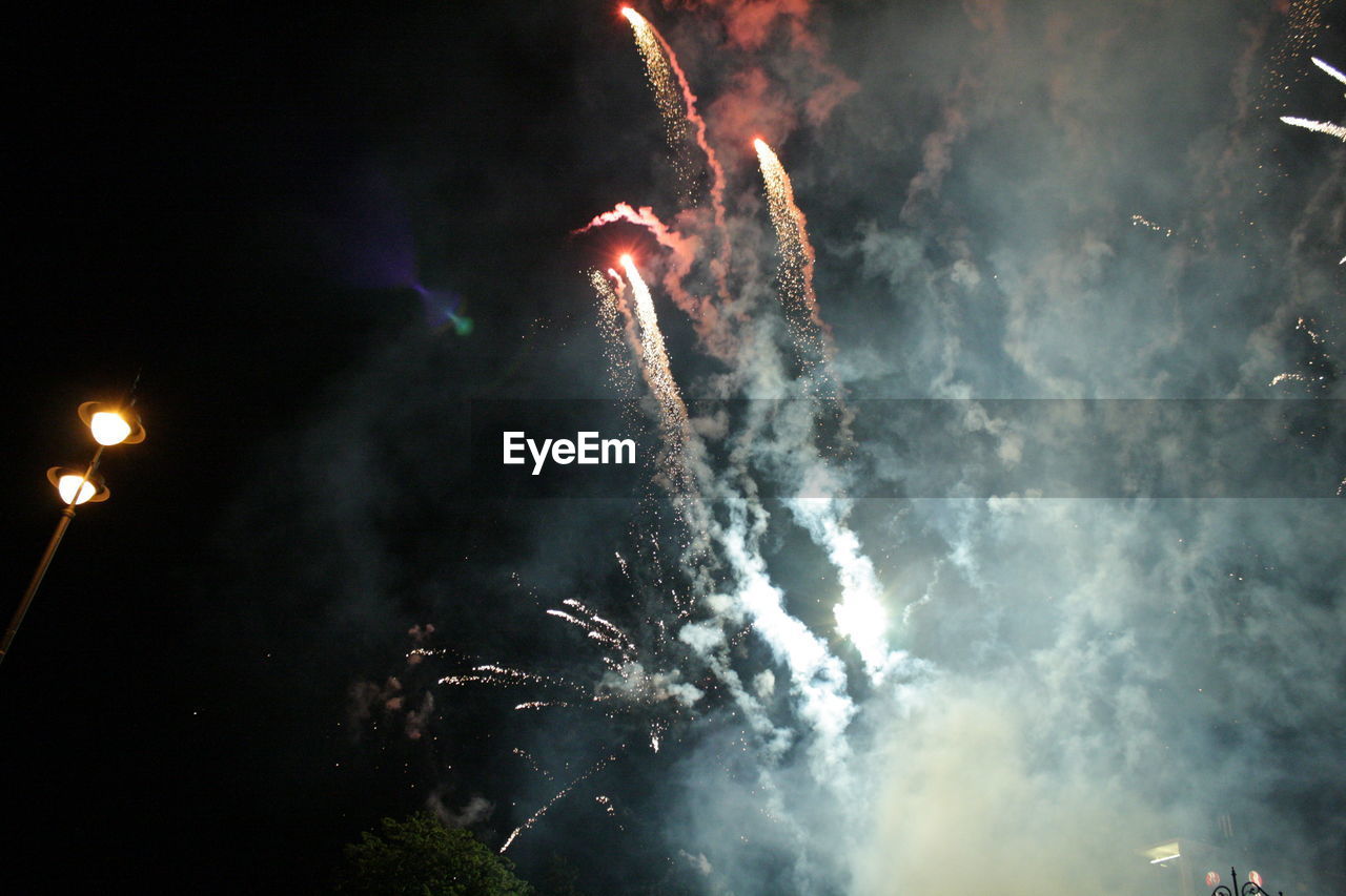 Low angle view of fireworks against sky at night