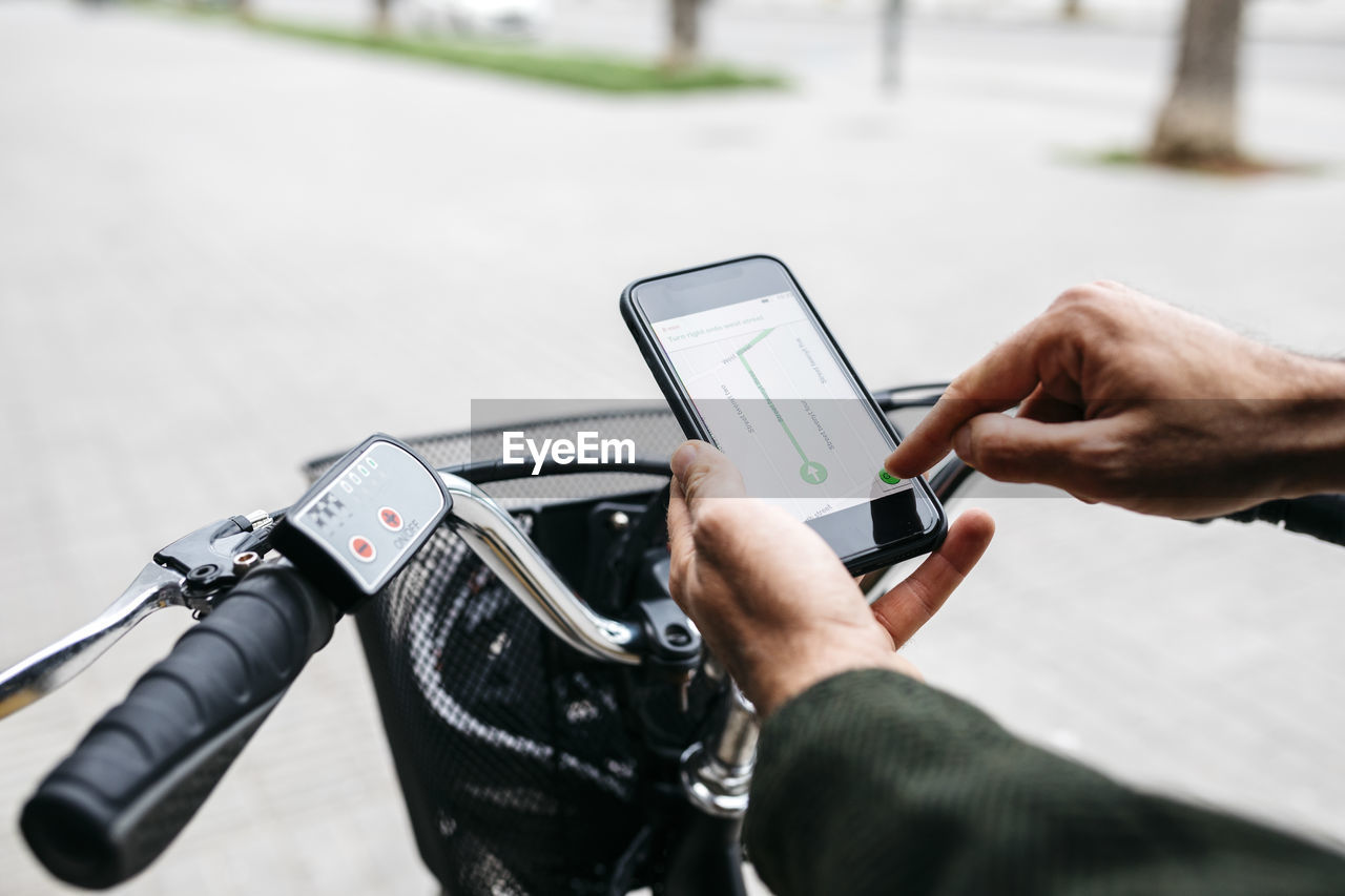 Close-up of man with e-bikeusing smartphone navigation system