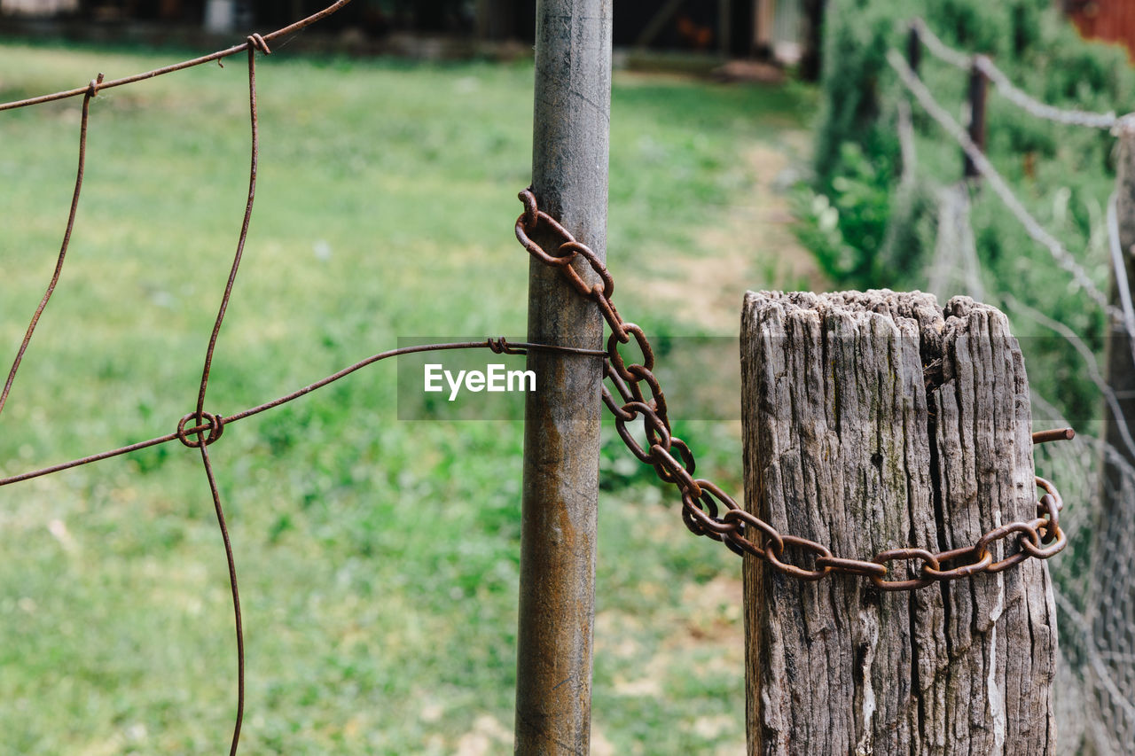 Close-up of fence by wooden post