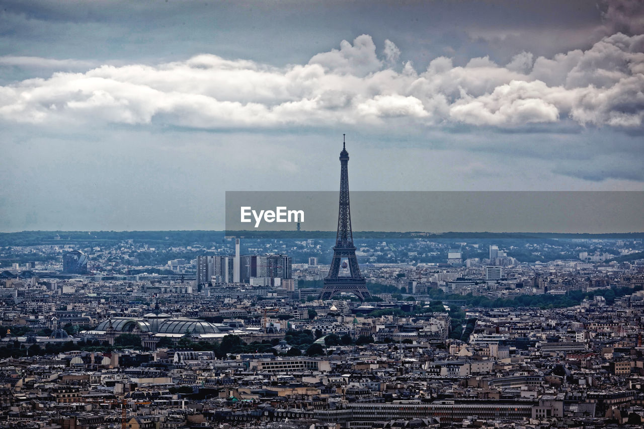 Eiffel tower amidst cityscape against sky