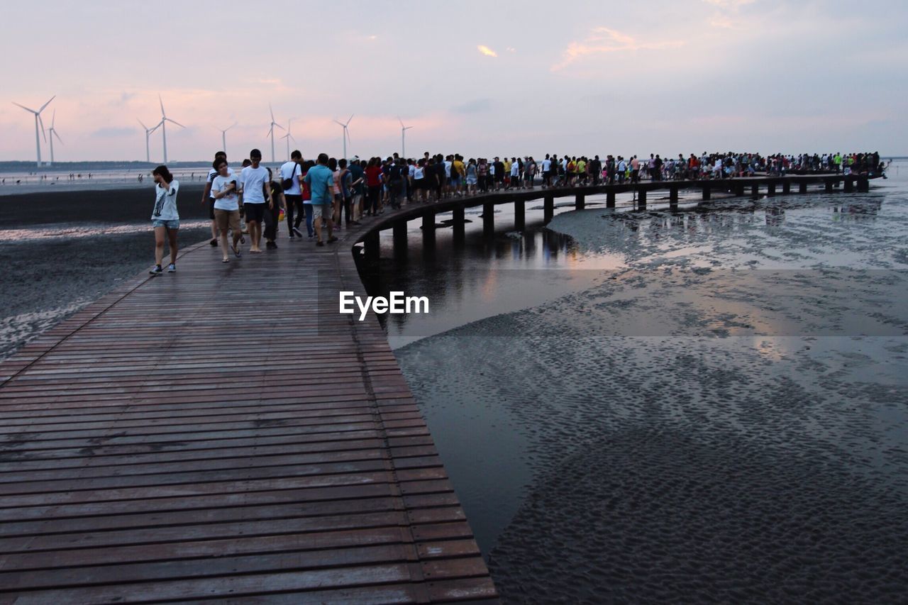 Scenic view of people walking on jetty at sea
