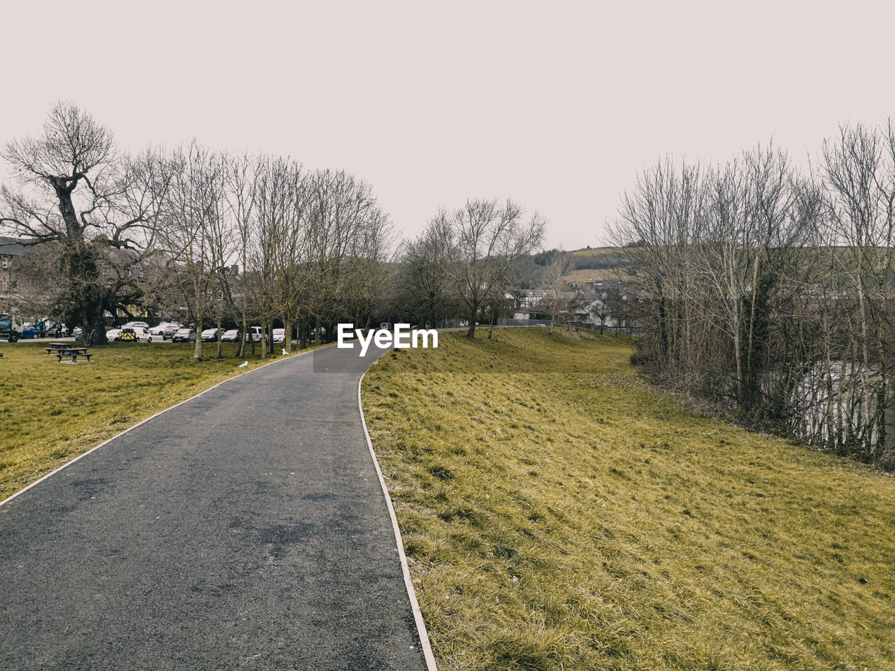 Empty road amidst field against clear sky