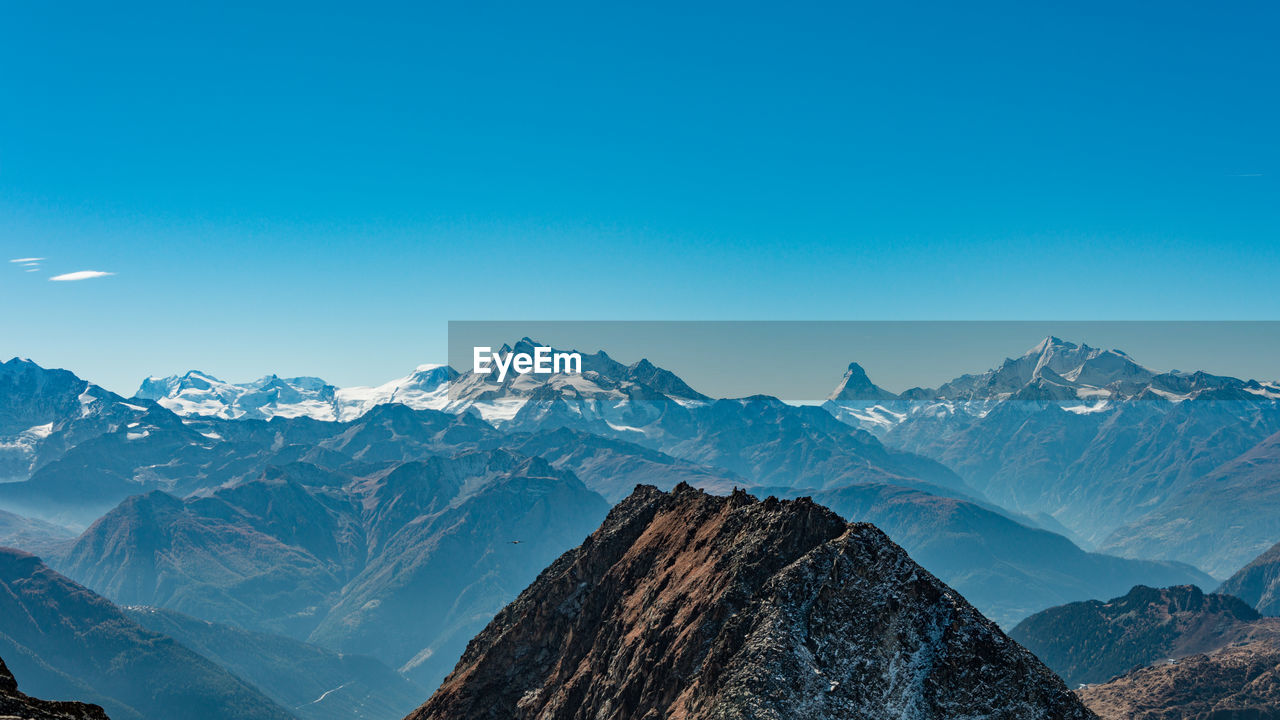 Scenic view of snowcapped mountains against clear blue sky