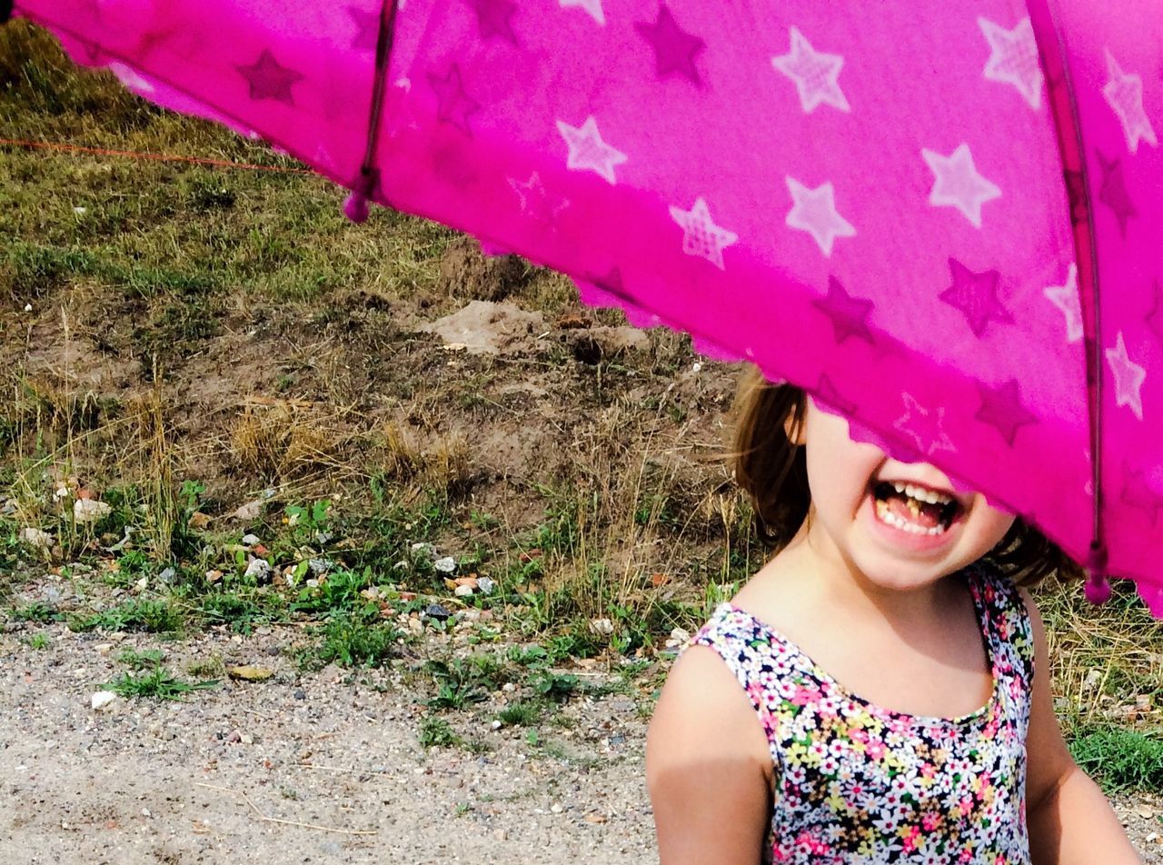 Cheerful girl under pink umbrella