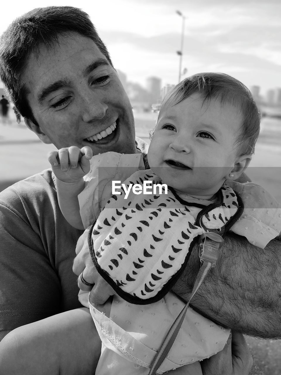 Close-up of smiling father carrying daughter against sky