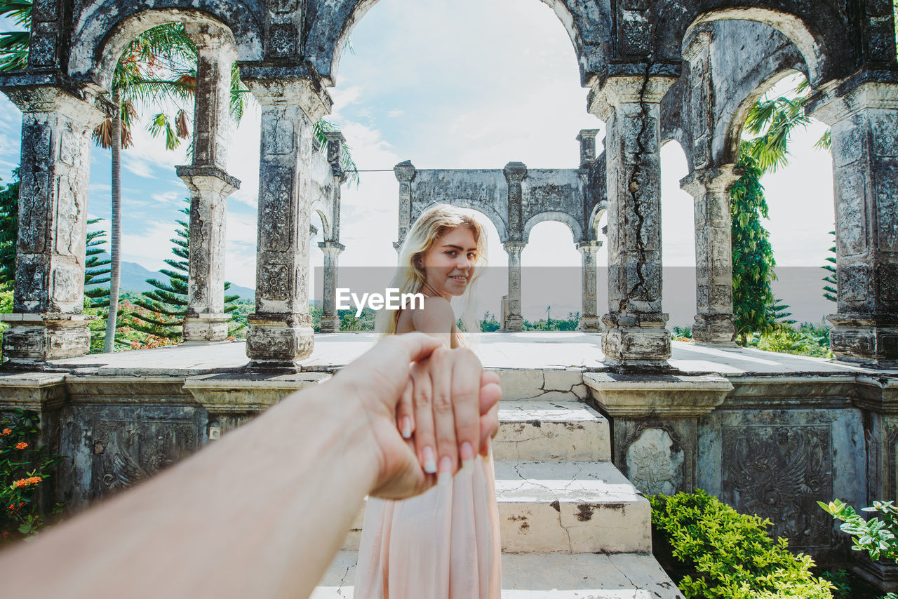 Young woman holding hand at abandoned structure