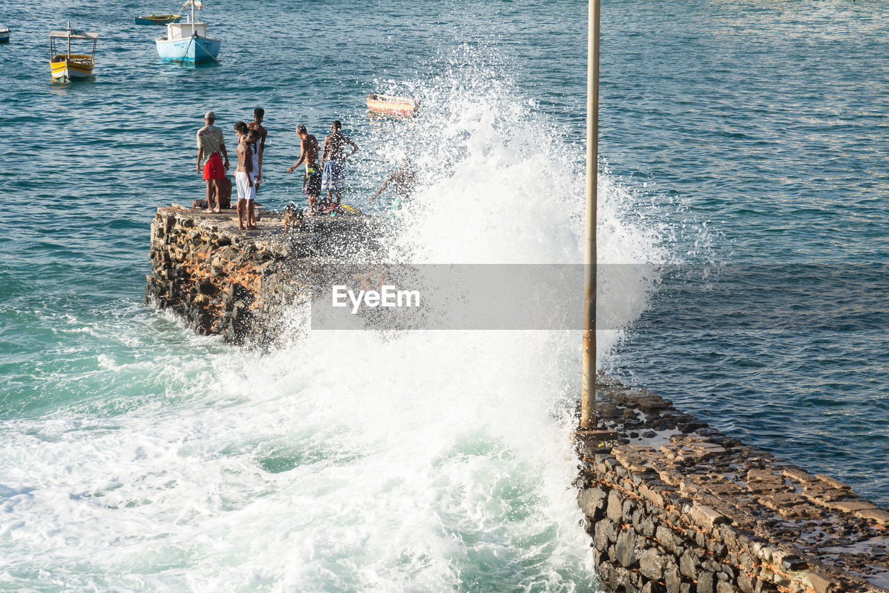 water, sea, motion, shore, wave, ocean, vehicle, wind wave, group of people, coast, men, day, nature, boating, splashing, sports, beauty in nature, lifestyles, nautical vessel, high angle view, water sports, outdoors, transportation, leisure activity, rock, surfing, scenics - nature, boat, waterfront, beach, breakwater, watercraft