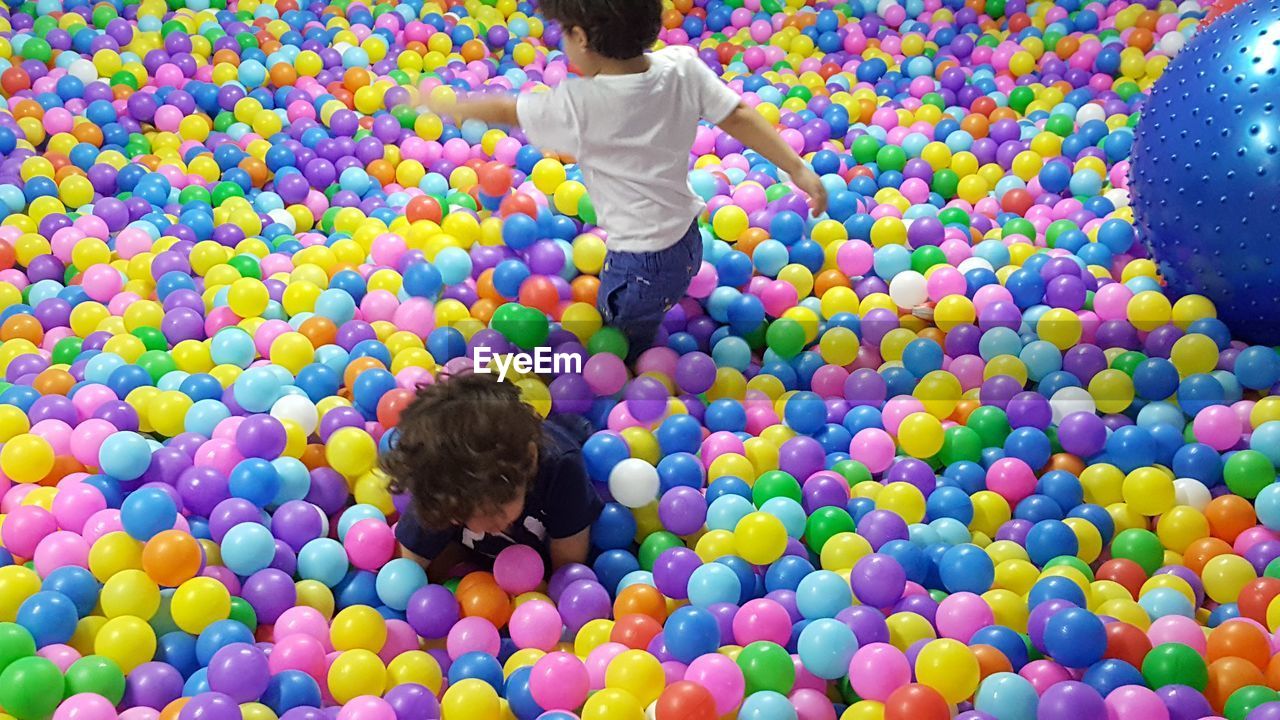 High angle view of brothers playing in colorful ball pool
