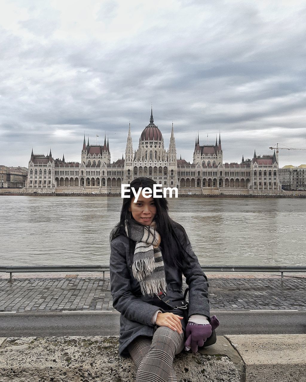 Portrait of woman sitting against parliament building