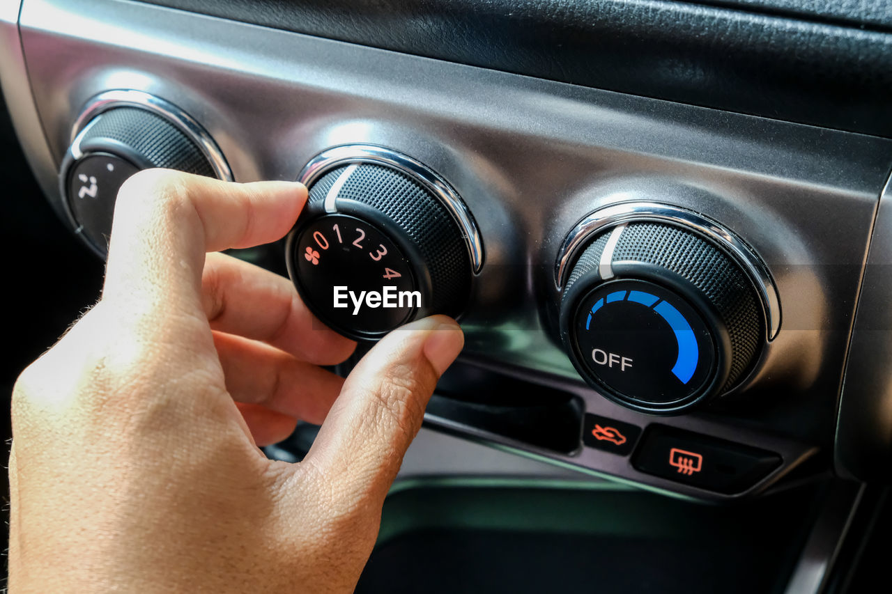 Close-up of hand adjusting knob in car