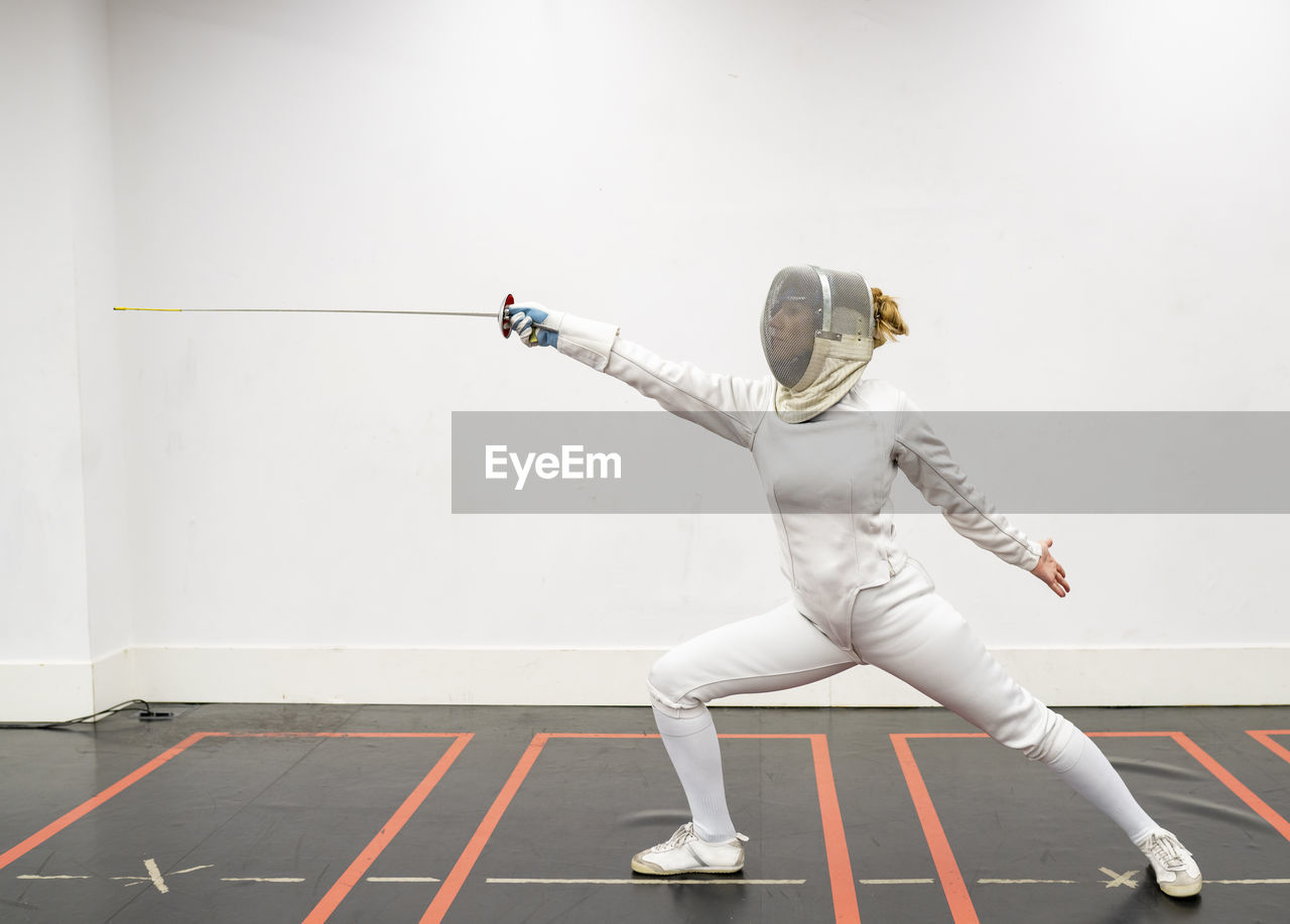 Woman in fencing outfit practicing at gym