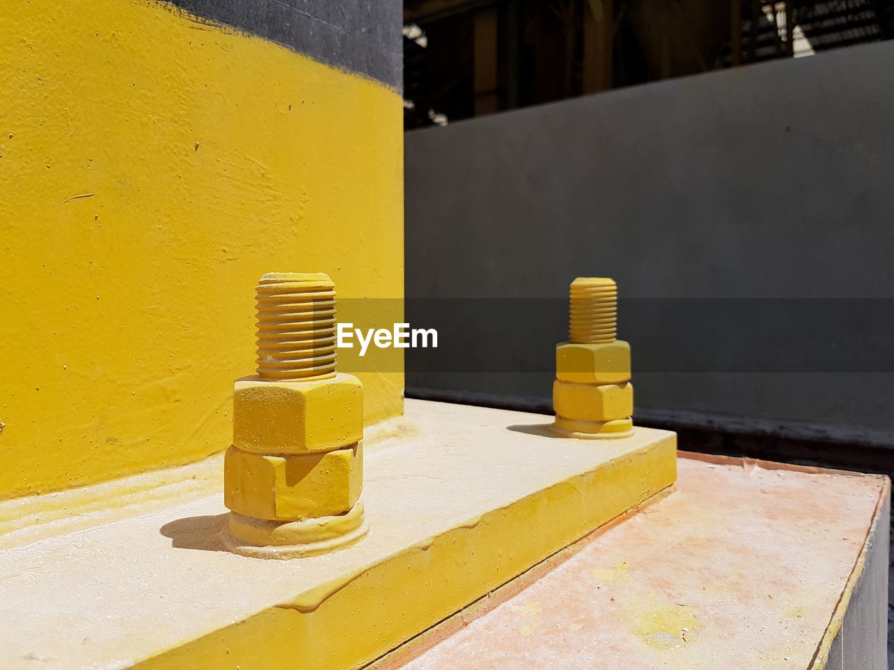 Close-up of yellow metal on table against wall