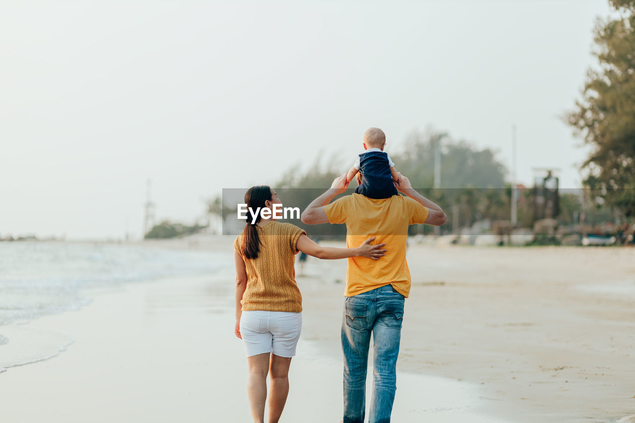 Rear view of people on beach against sky