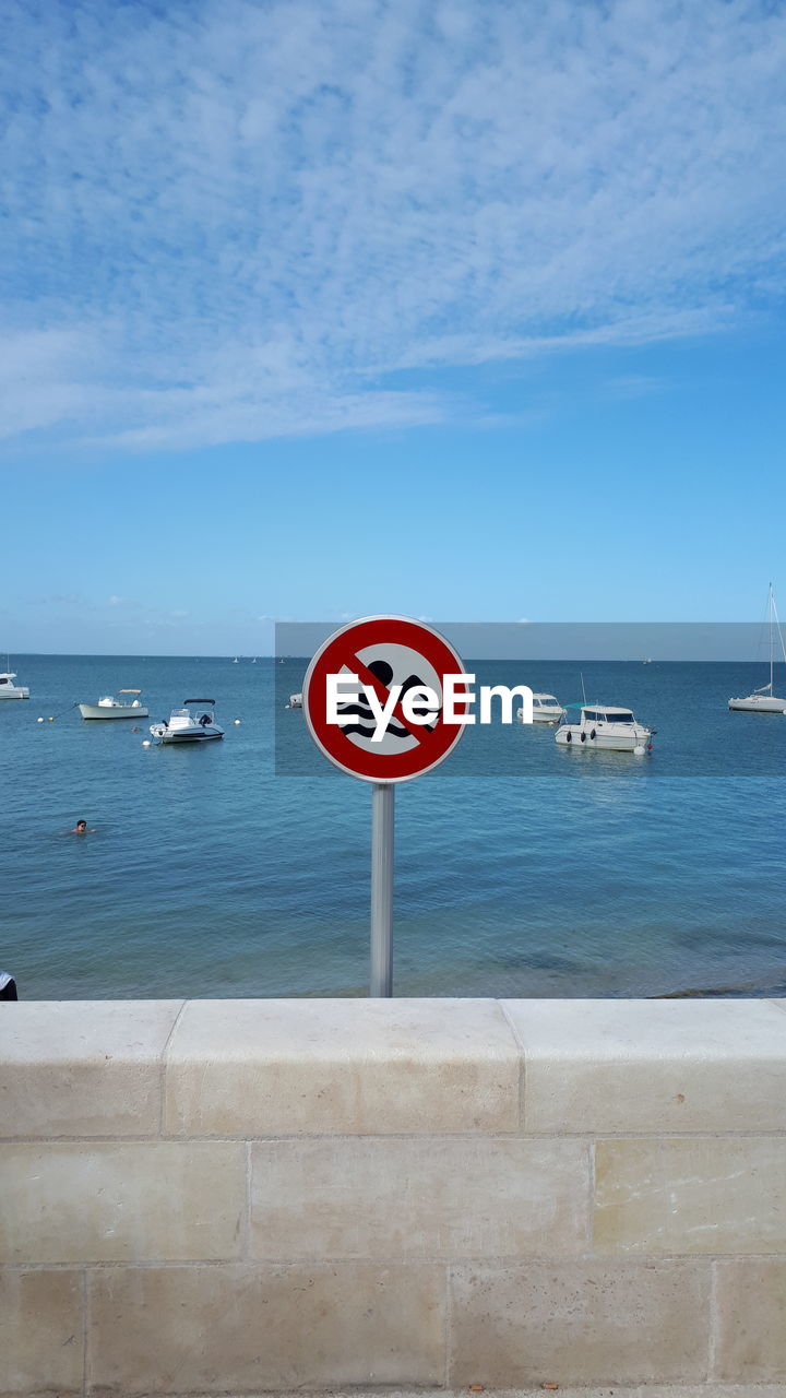 WARNING SIGN ON SEA AGAINST SKY