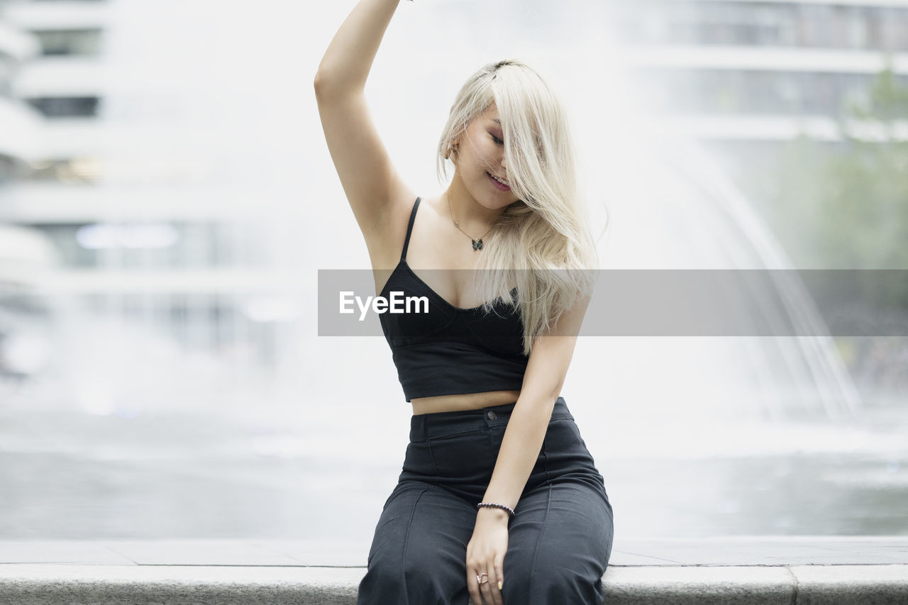 Young woman looking away while standing in city