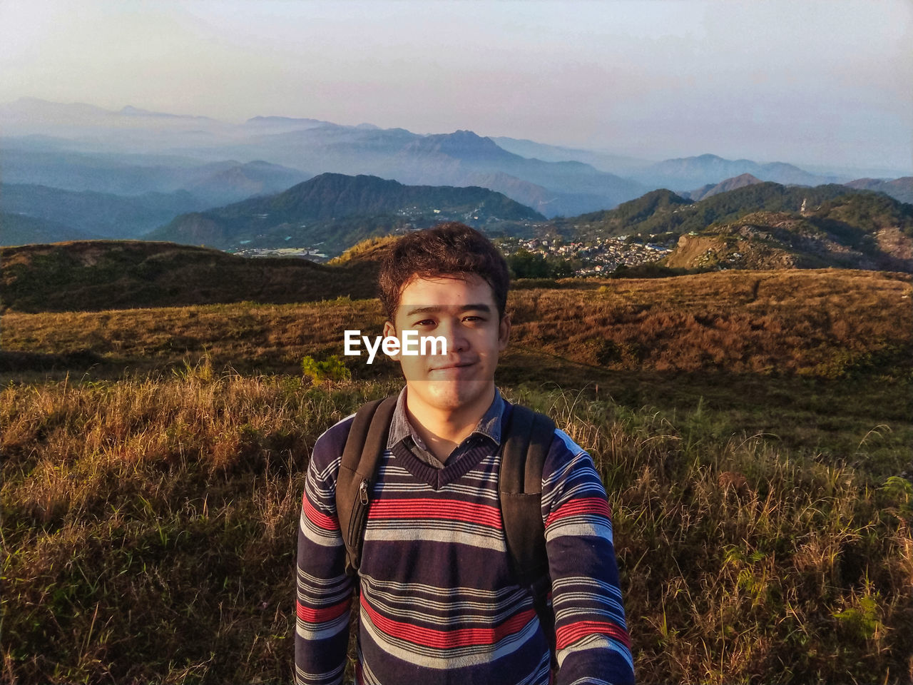 Portrait of young man standing on mountain during sunset