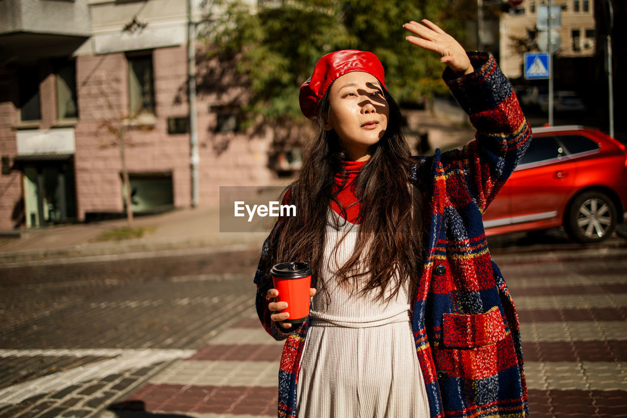 Asian girl with coffee walking on street in autumn