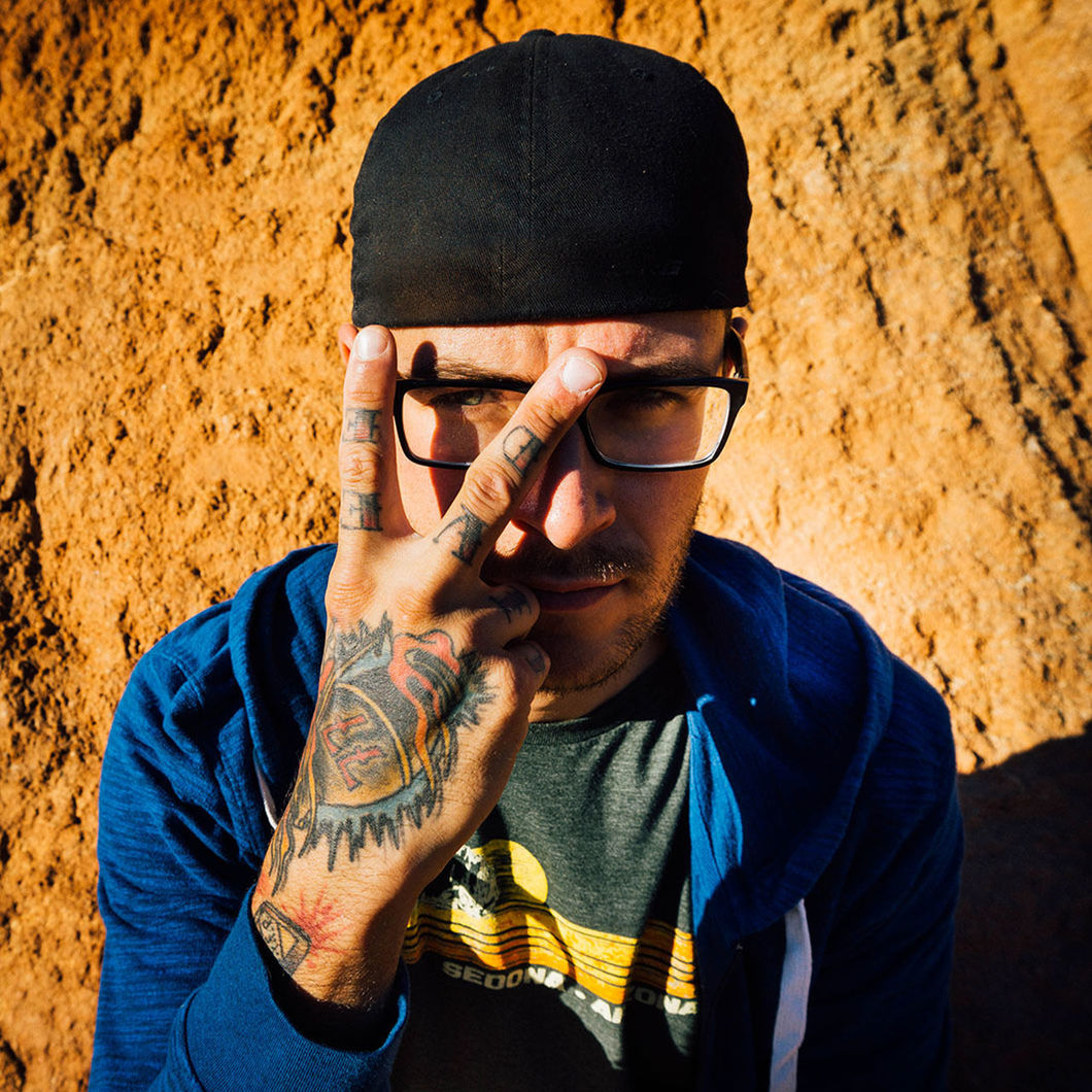 High angle view portrait of tattooed man gesturing peace sign against rock