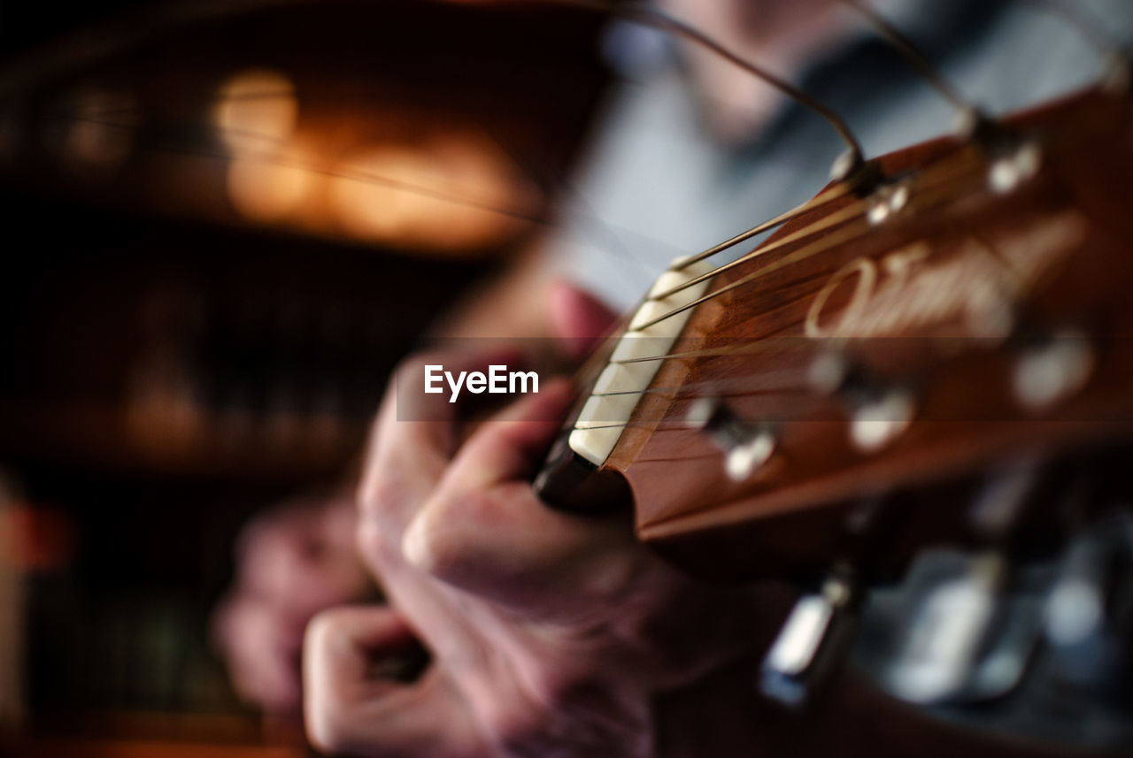 Midsection of man playing acoustic guitar