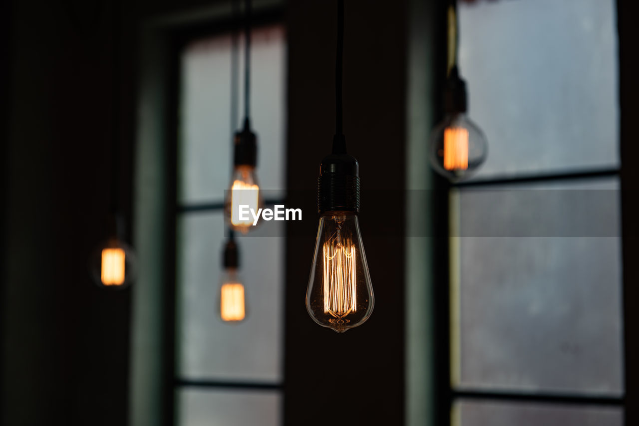 Close-up of illuminated pendant lights in darkroom