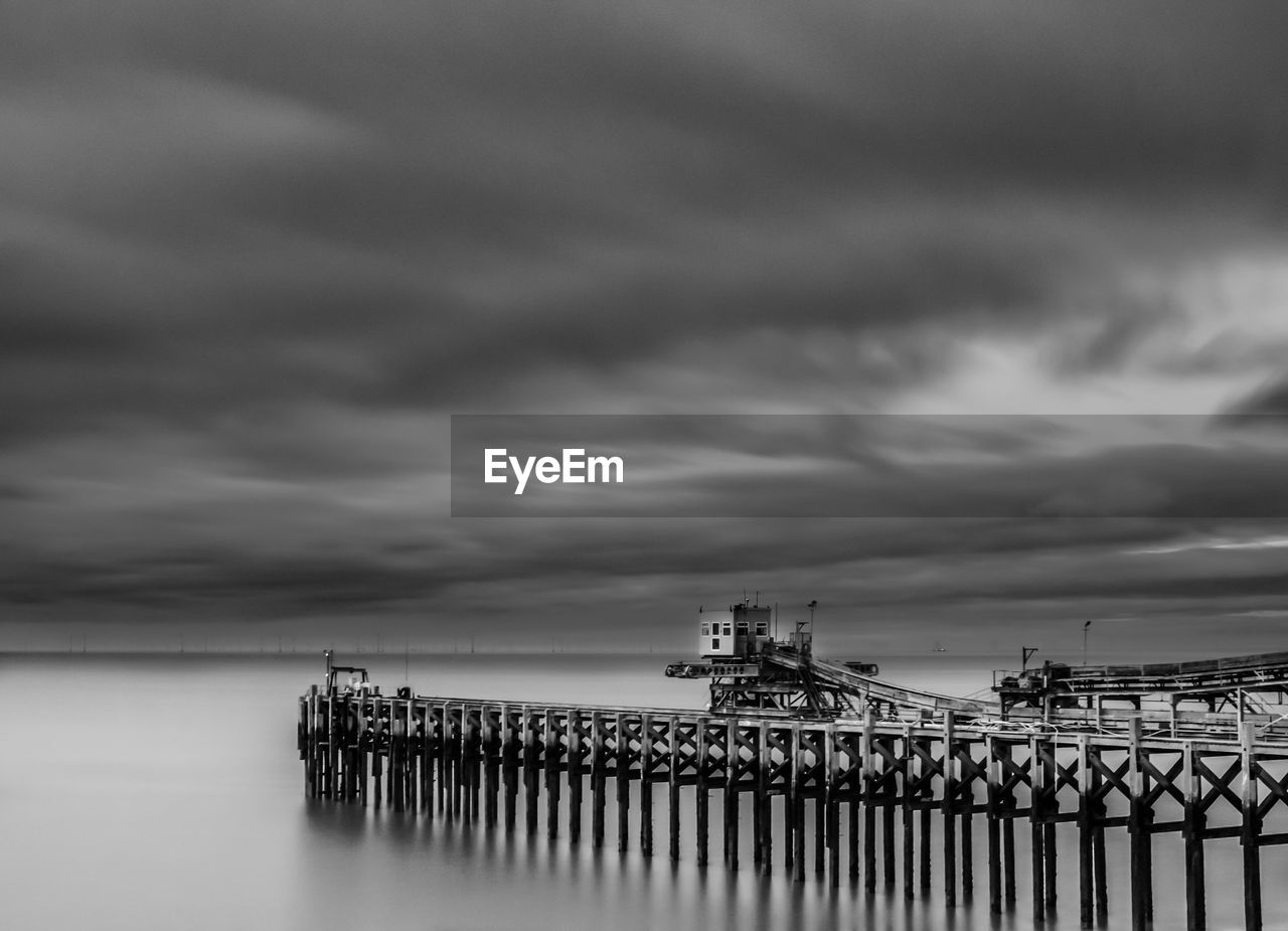 Pier on sea against cloudy sky