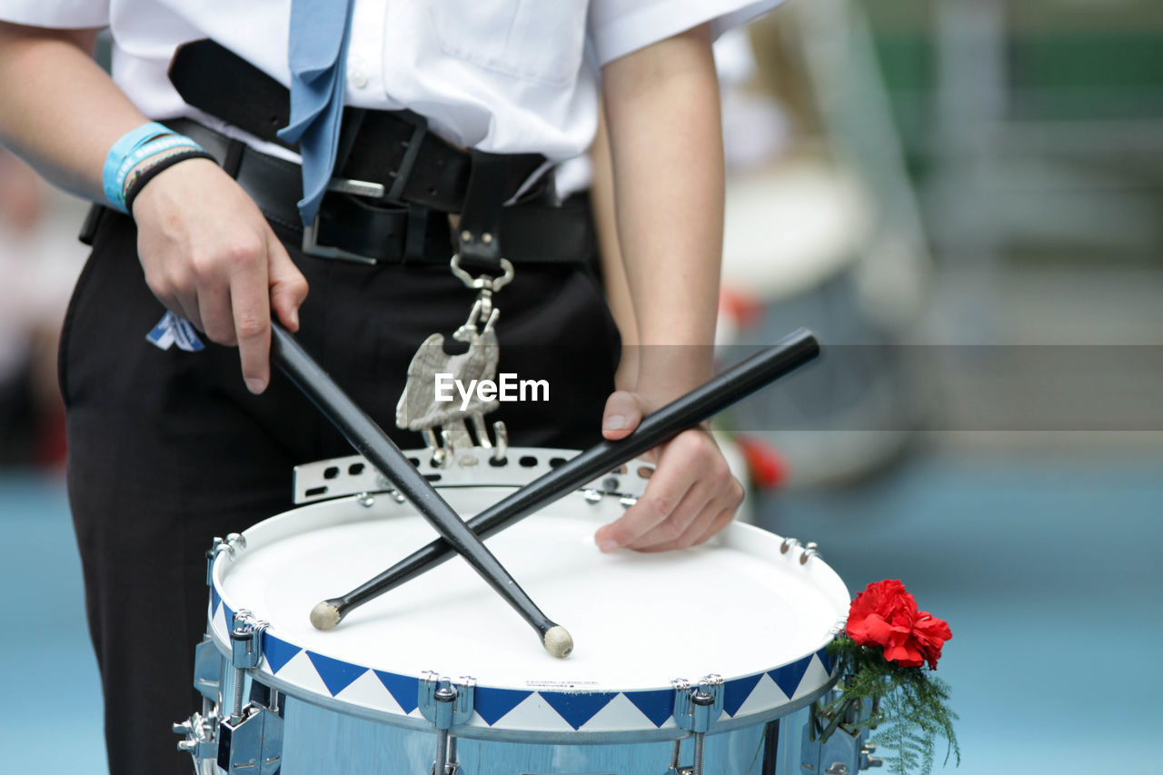 Midsection of man playing drum at music concert