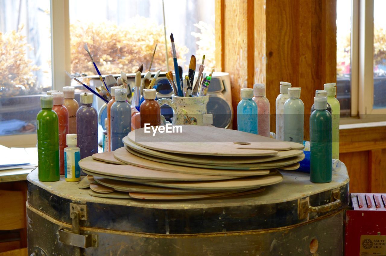 Colorful paint bottles with palette on drum at workshop