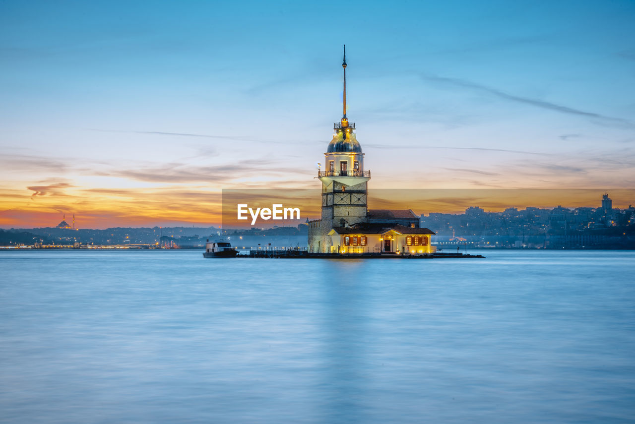 ILLUMINATED BUILDING BY SEA AGAINST SKY