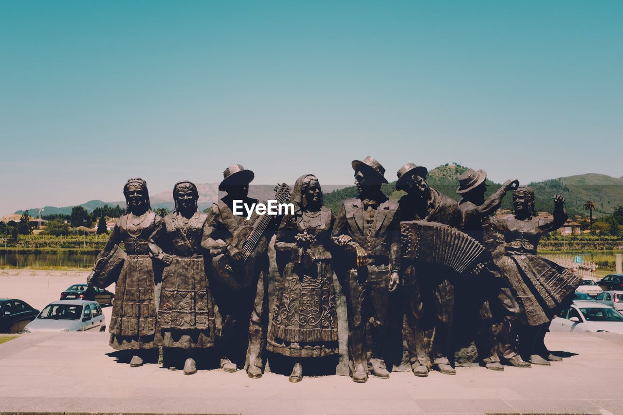 GROUP OF PEOPLE IN FRONT OF BUILT STRUCTURE AGAINST SKY