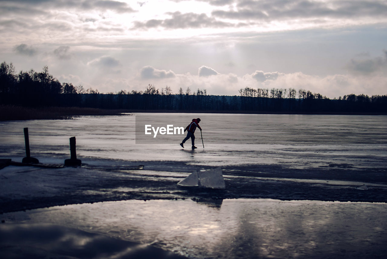Full length of person walking on frozen lake against sky