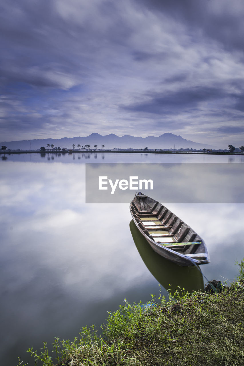 Boat moored in lake against sky