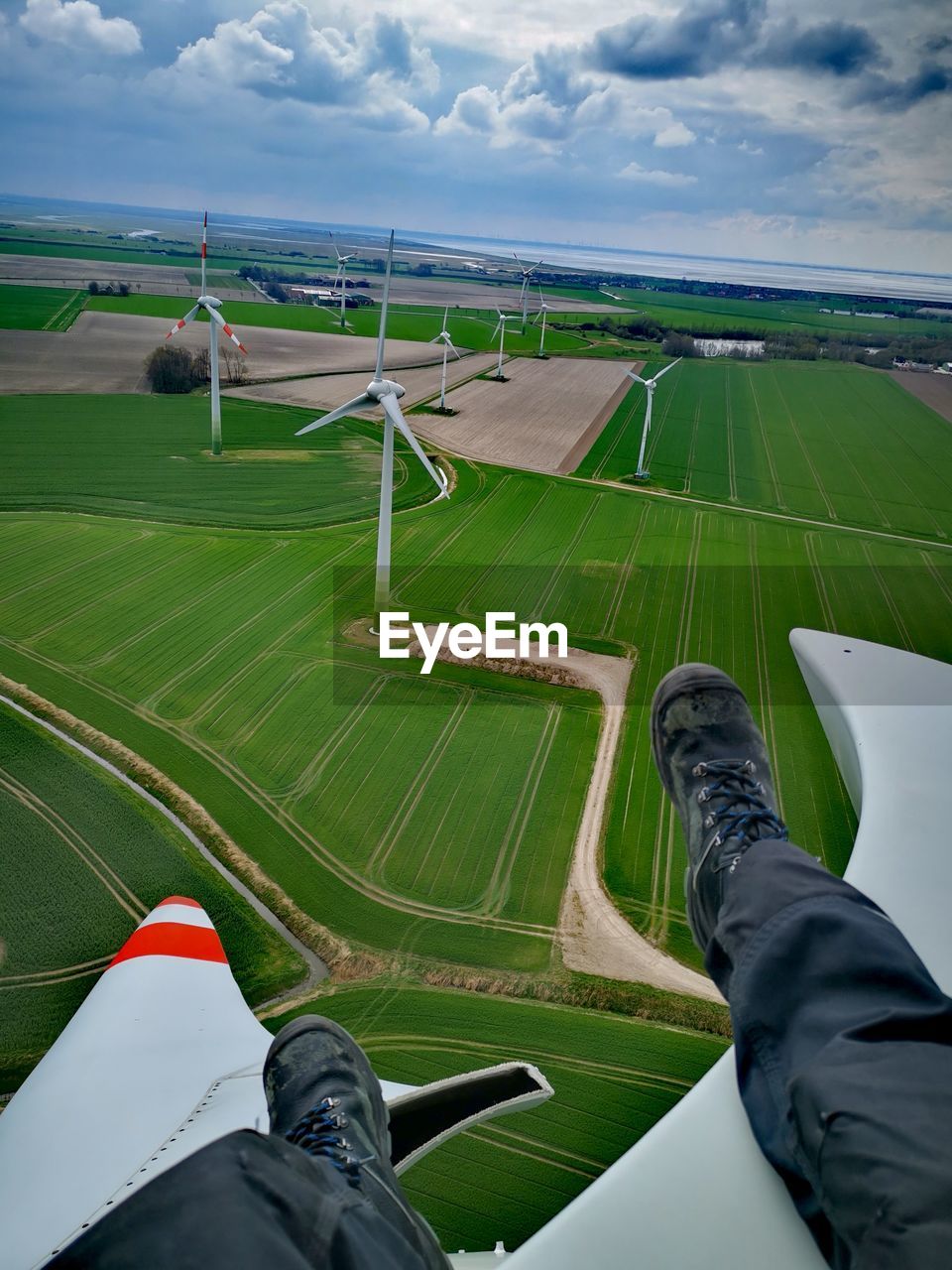 Low section of man on windmill at agricultural field